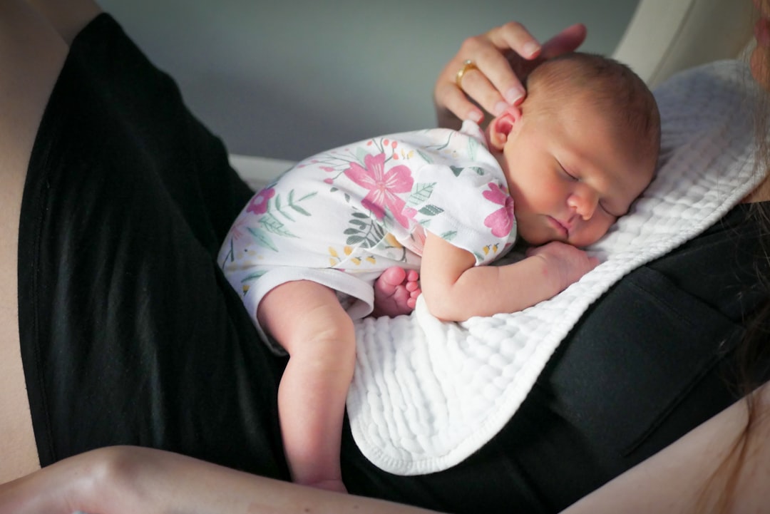 Mamma con neonato in braccio, sguardo stanco e pensieroso, luce naturale